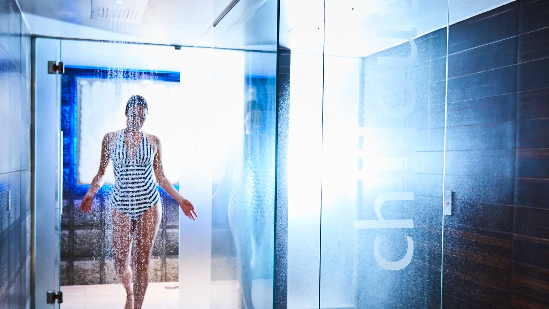 woman walking out of glass shower with water droplets