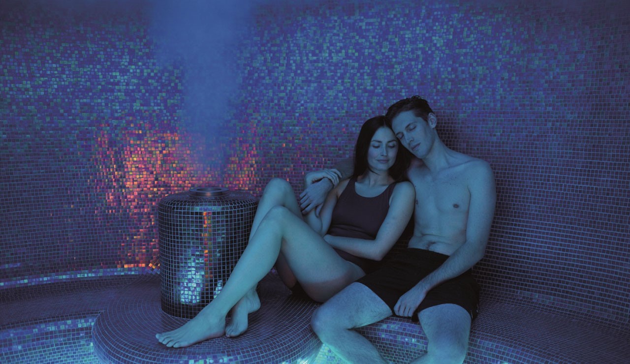couple relaxing in steam room with tiled mosaic walls