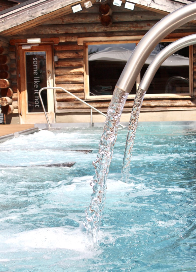 water flowing from metal pipes into outdoor wooden hot tub