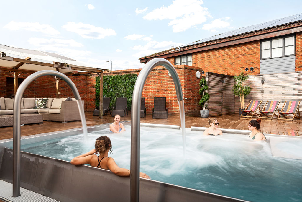 four women relaxing in outdoor jacuzzi pool area