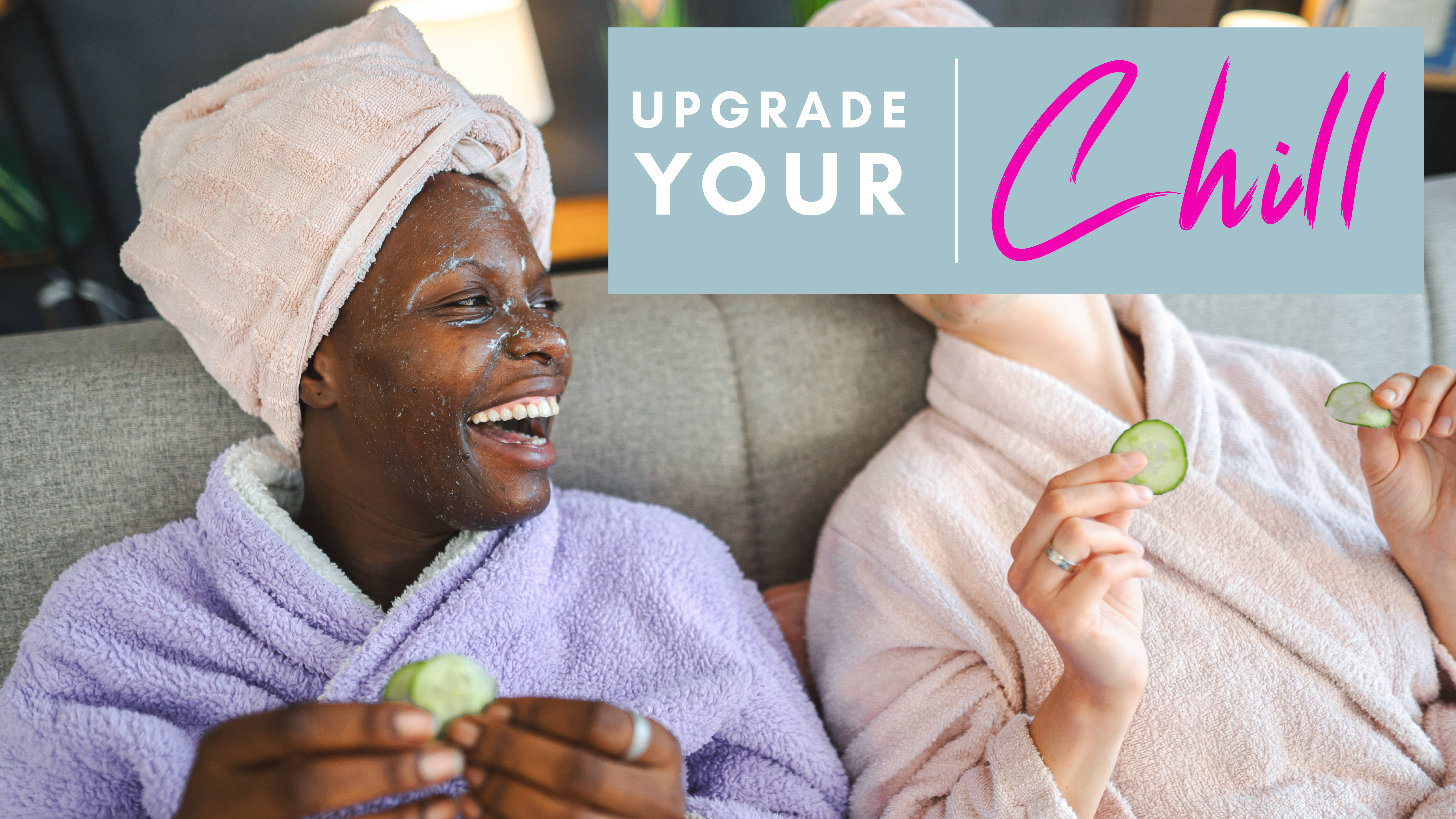 two women in bathrobes smiling with cucumber slices