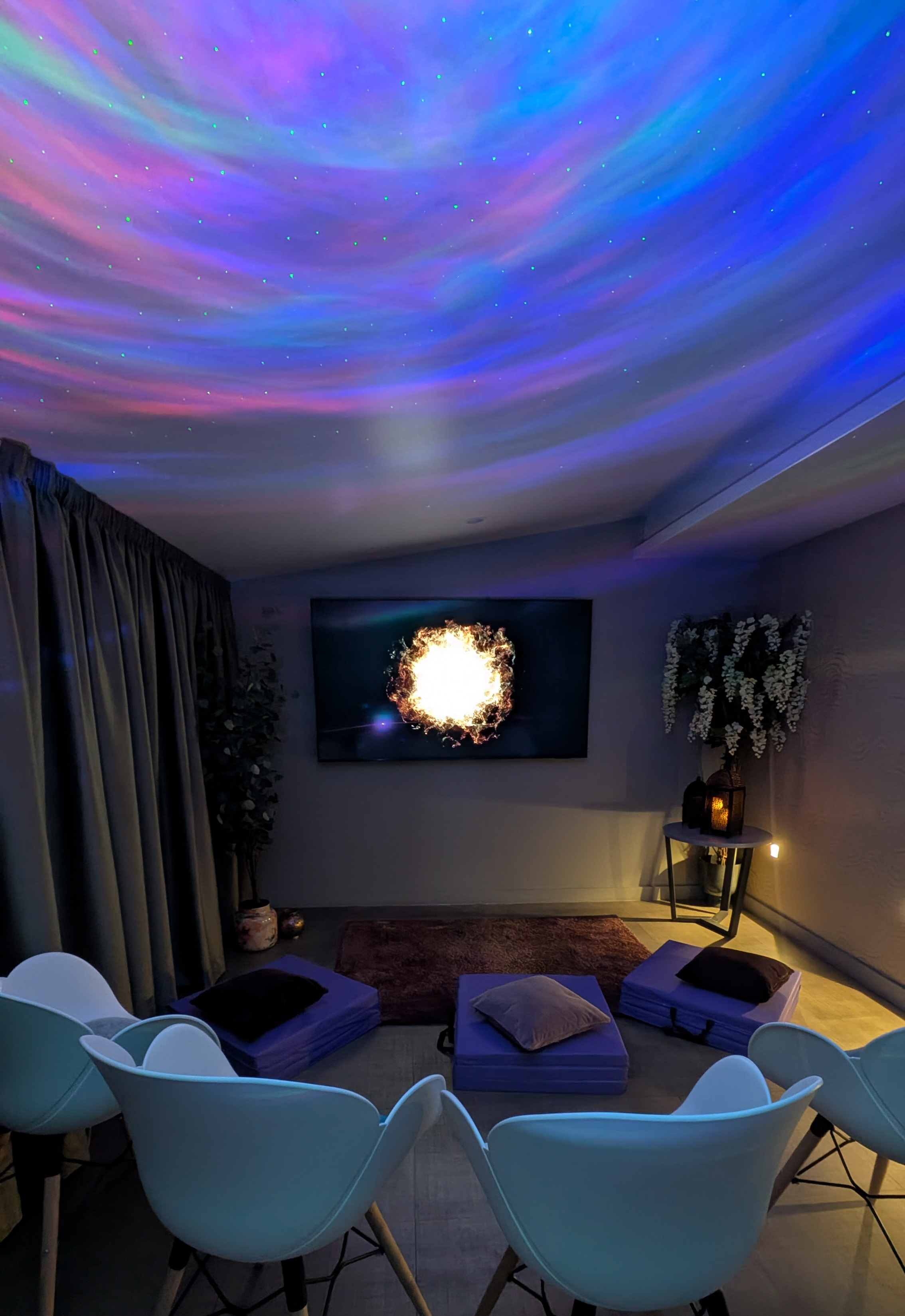 room with chairs cushions and starry sky projector lighting