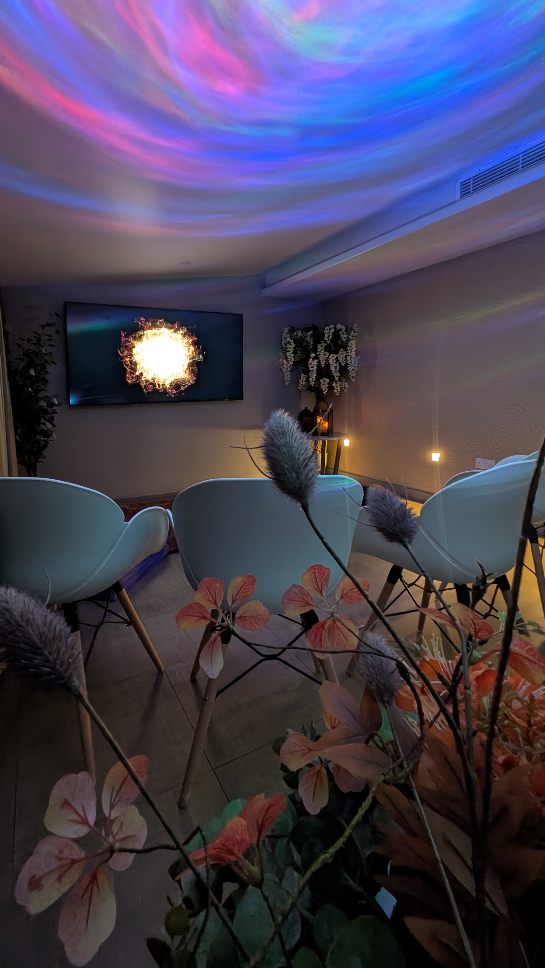 cozy room with chairs tv and colourful ceiling lights